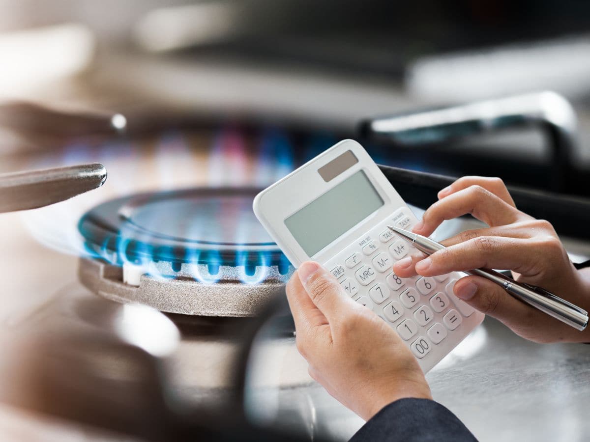 Fornello gas, con mani che tengono una calcolatrice
