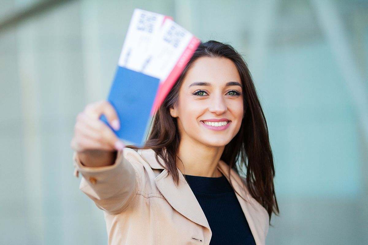 ragazze che mostra felice i biglietti aerei acquistati
