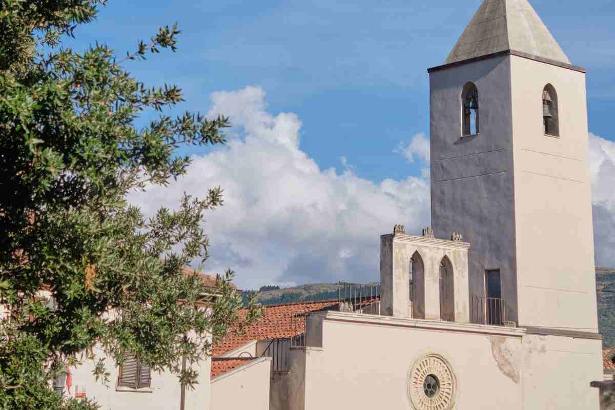 chiesa a Sadali con vegetazione, cielo azzurro e nuvole