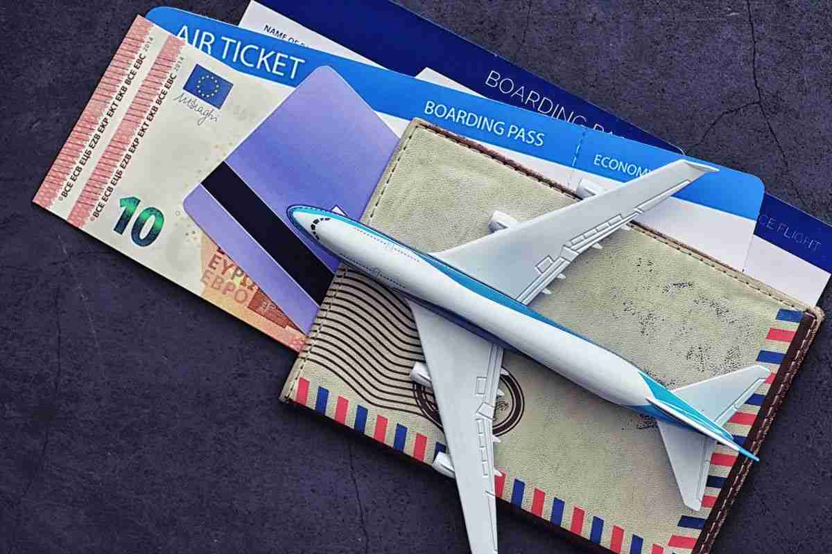 biglietto aereo, modellino di aeroplano, soldi in contanti in euro e carta di credito