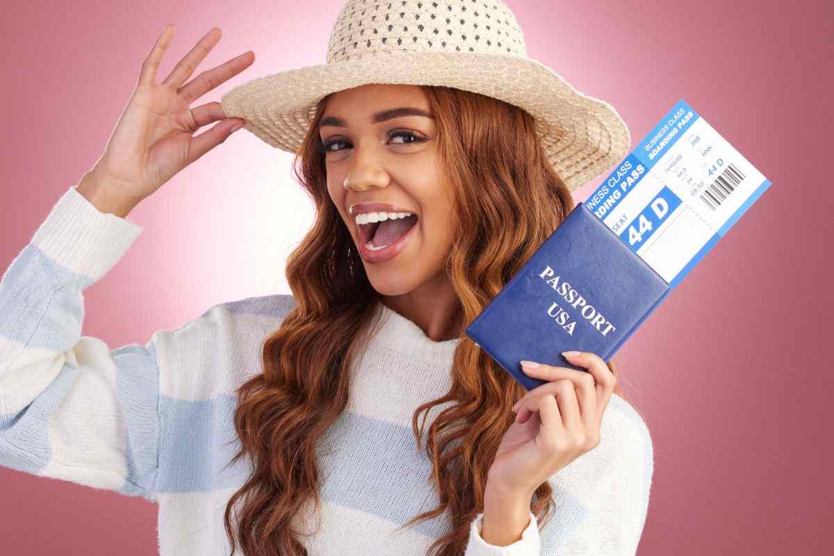 donna felice con cappello, in mano un biglietto aereo